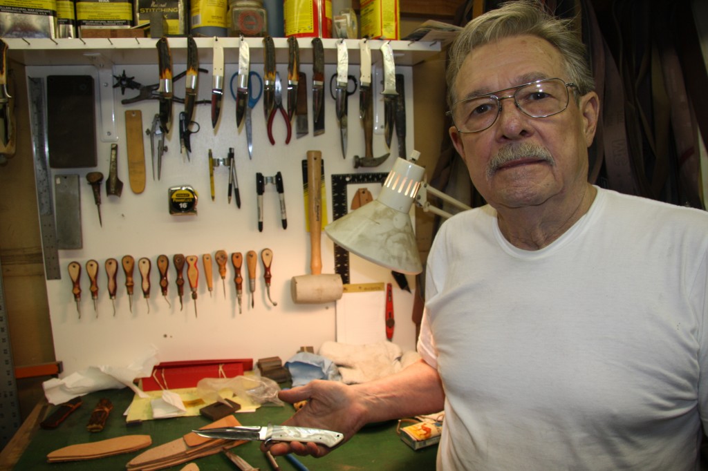 Jim Merritt in a knife shop, tools on the wall behind him