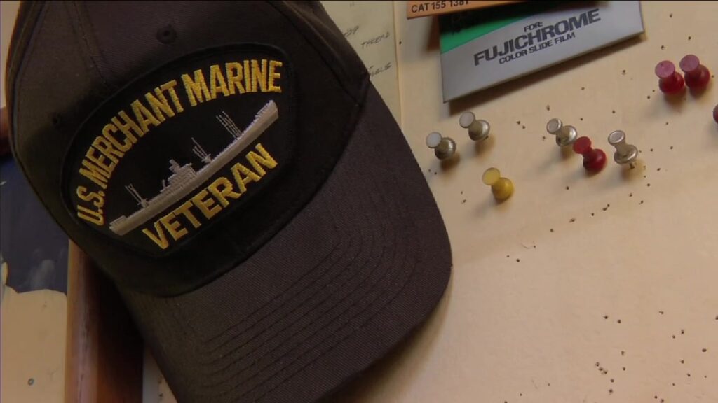 A U.S. Merchant Marine Veteran cap hanging on a corkboard in the knife shop